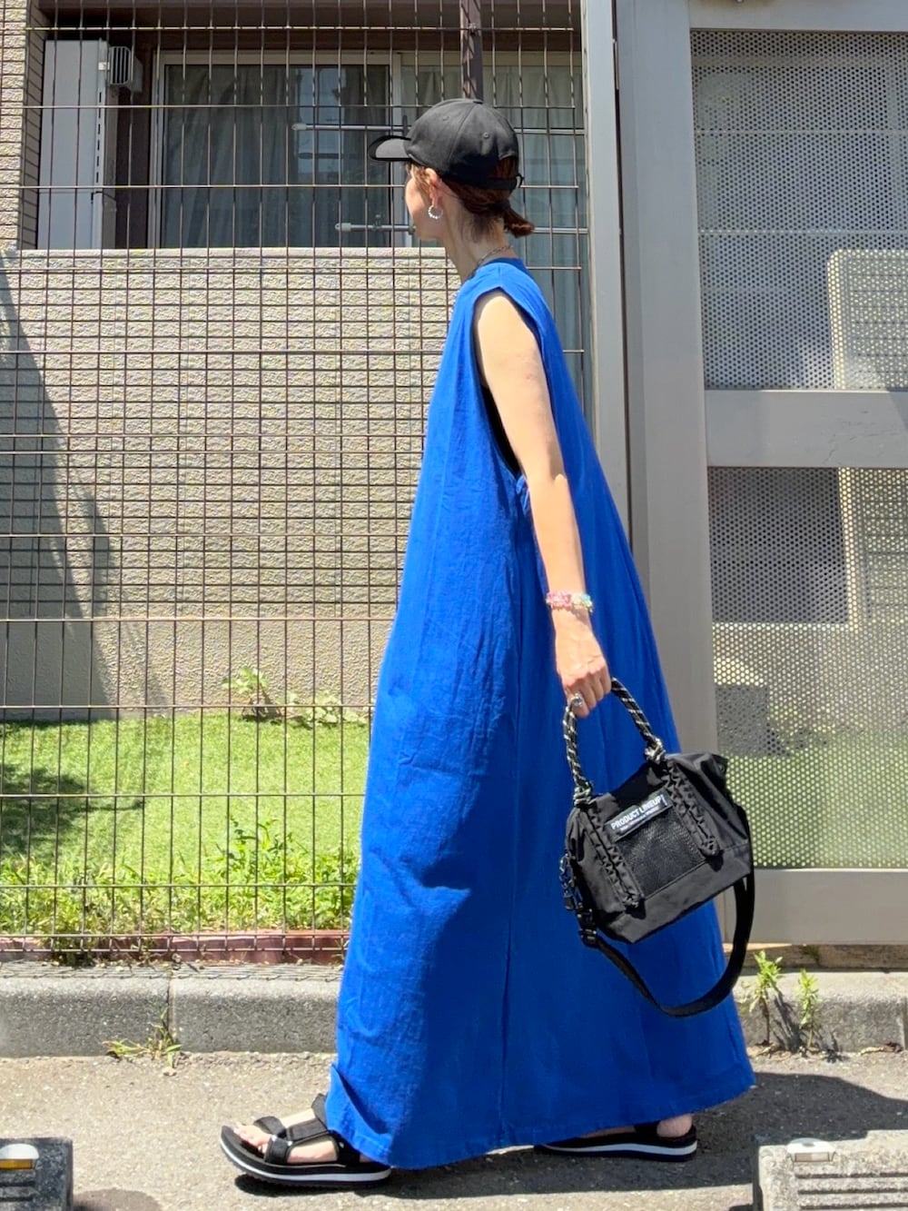 ブルー系のワンピース、ブラック系のトートバッグ、ブラック系のキャップを着用したレディースの夏コーディネートの3枚目の写真