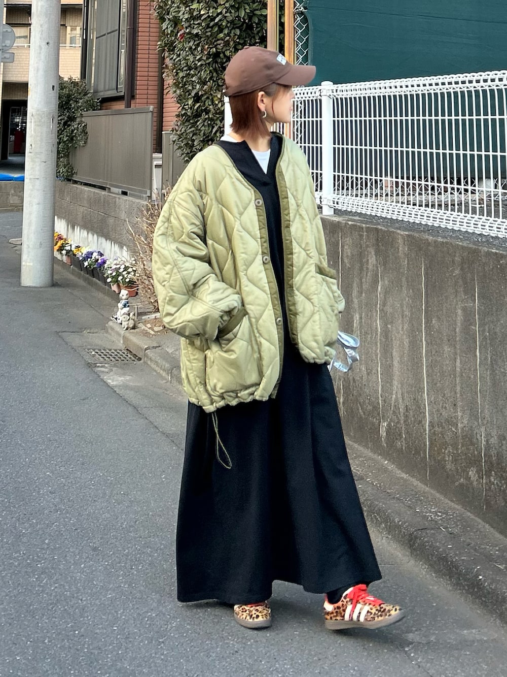 グリーン系のブルゾン、ブラック系のワンピース、シルバー系のクラッチバッグを着用したレディースの冬コーディネートの2枚目の写真