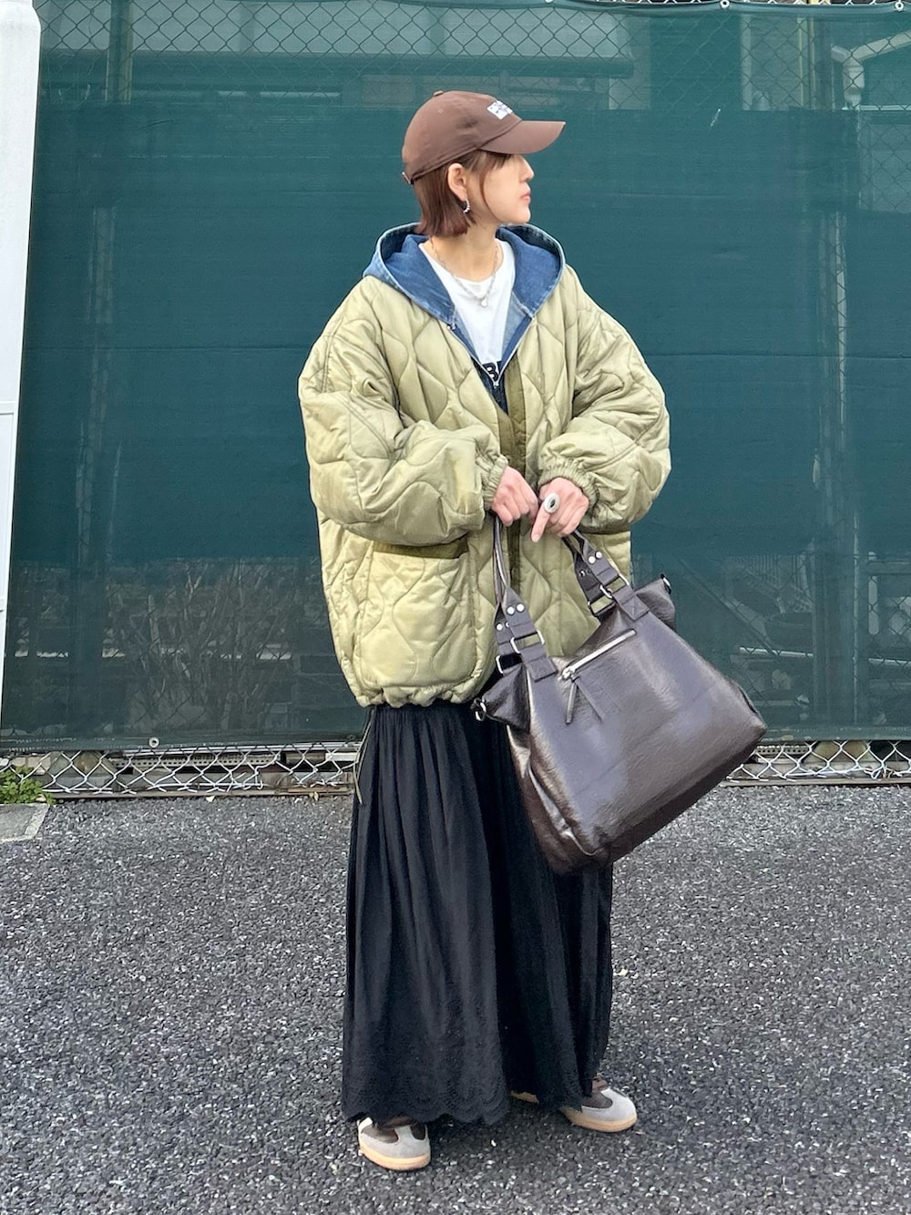 ブラック系のスカート、グリーン系のブルゾン、ブラウン系のトートバッグを着用したレディースの春コーディネートの2枚目の写真