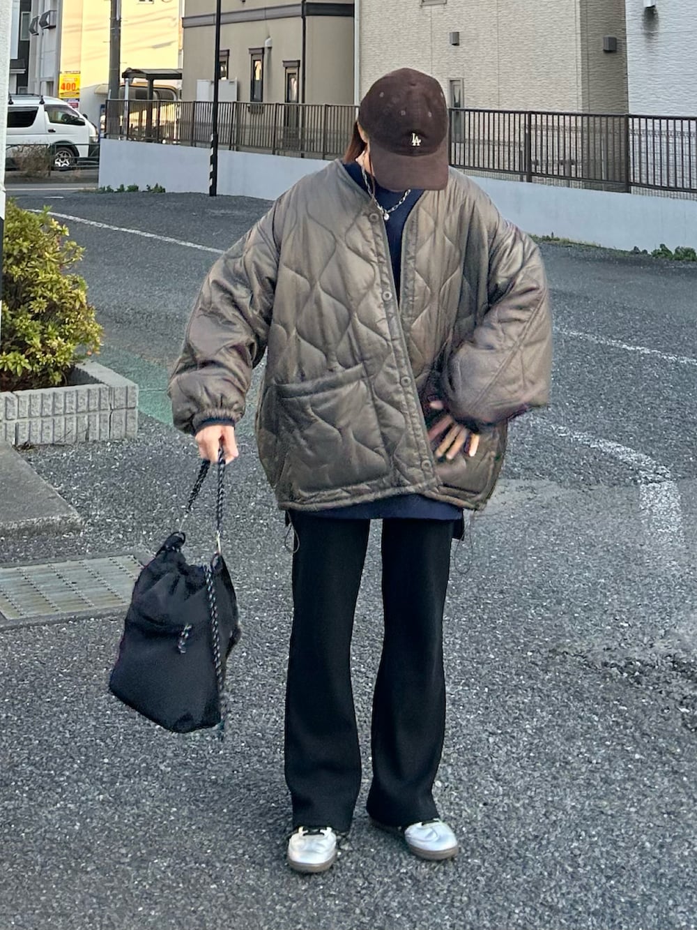 ブラウン系のブルゾン、ブルー系のスウェット、ブラック系のトートバッグを着用したレディースの冬コーディネートの2枚目の写真