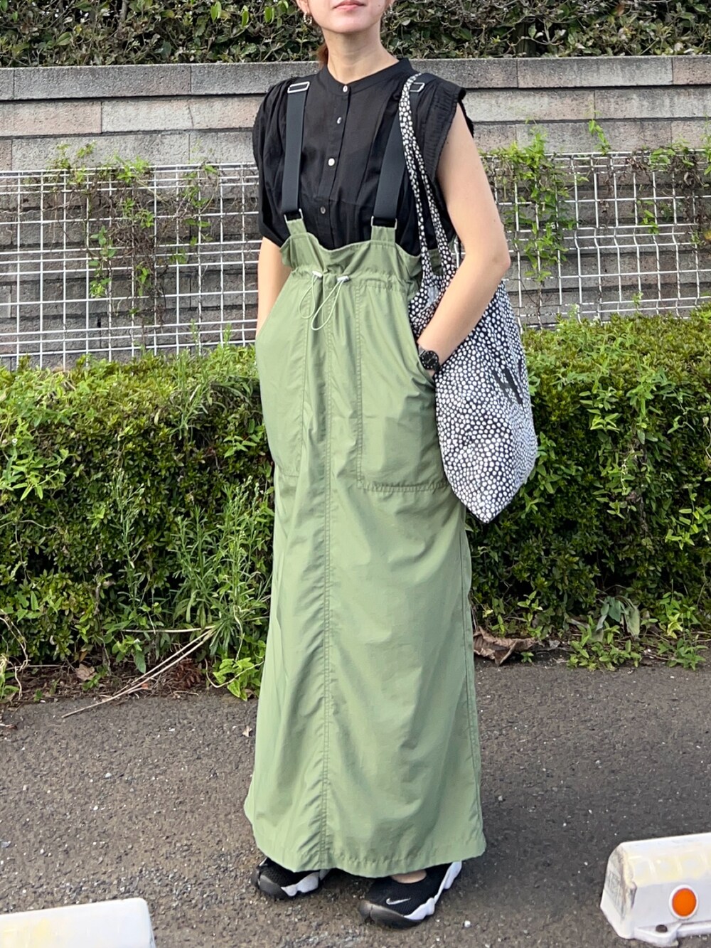 ブラック系のシャツ/ブラウス、グリーン系のジャンパースカート、ブラック系のスニーカーを着用したレディースの夏コーディネートの2枚目の写真