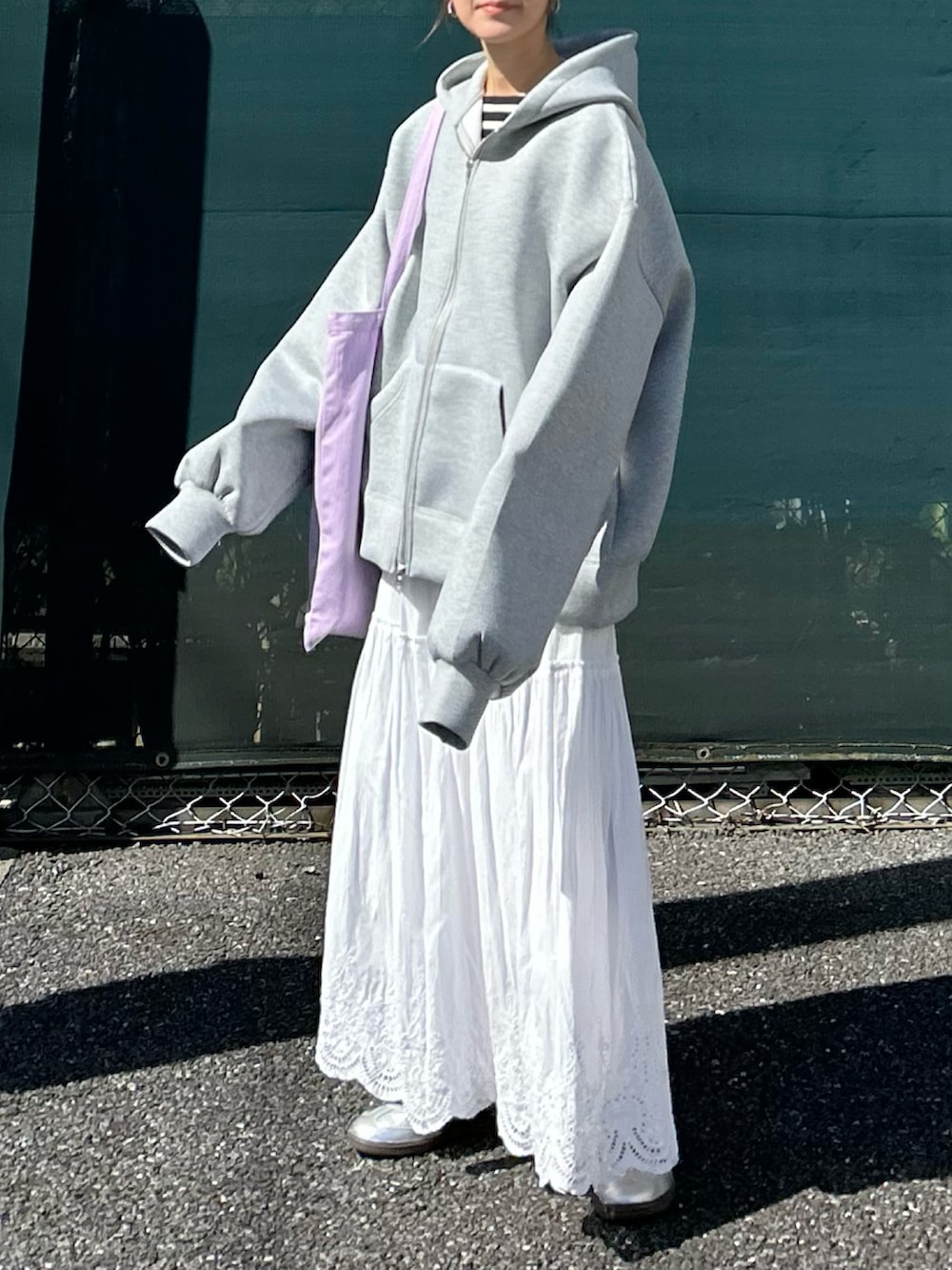 グレー系のパーカー、ホワイト系のスカート、パープル系のトートバッグを着用したレディースの秋コーディネートの5枚目の写真