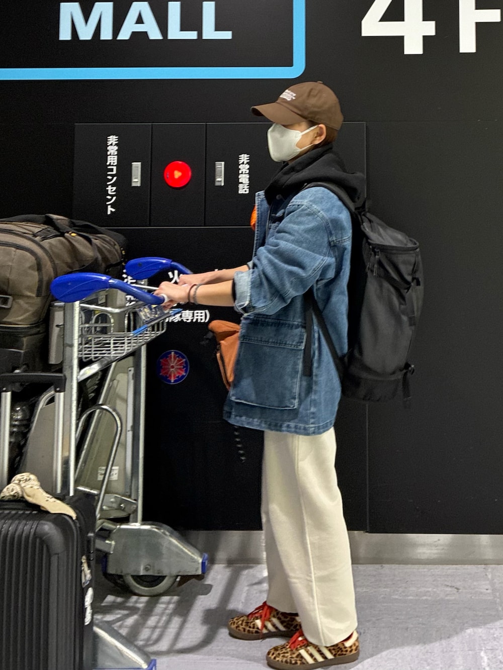 ブルー系のデニムジャケット、ブラック系のパーカー、オレンジ系のショルダーバッグを着用したレディースの春コーディネートの2枚目の写真