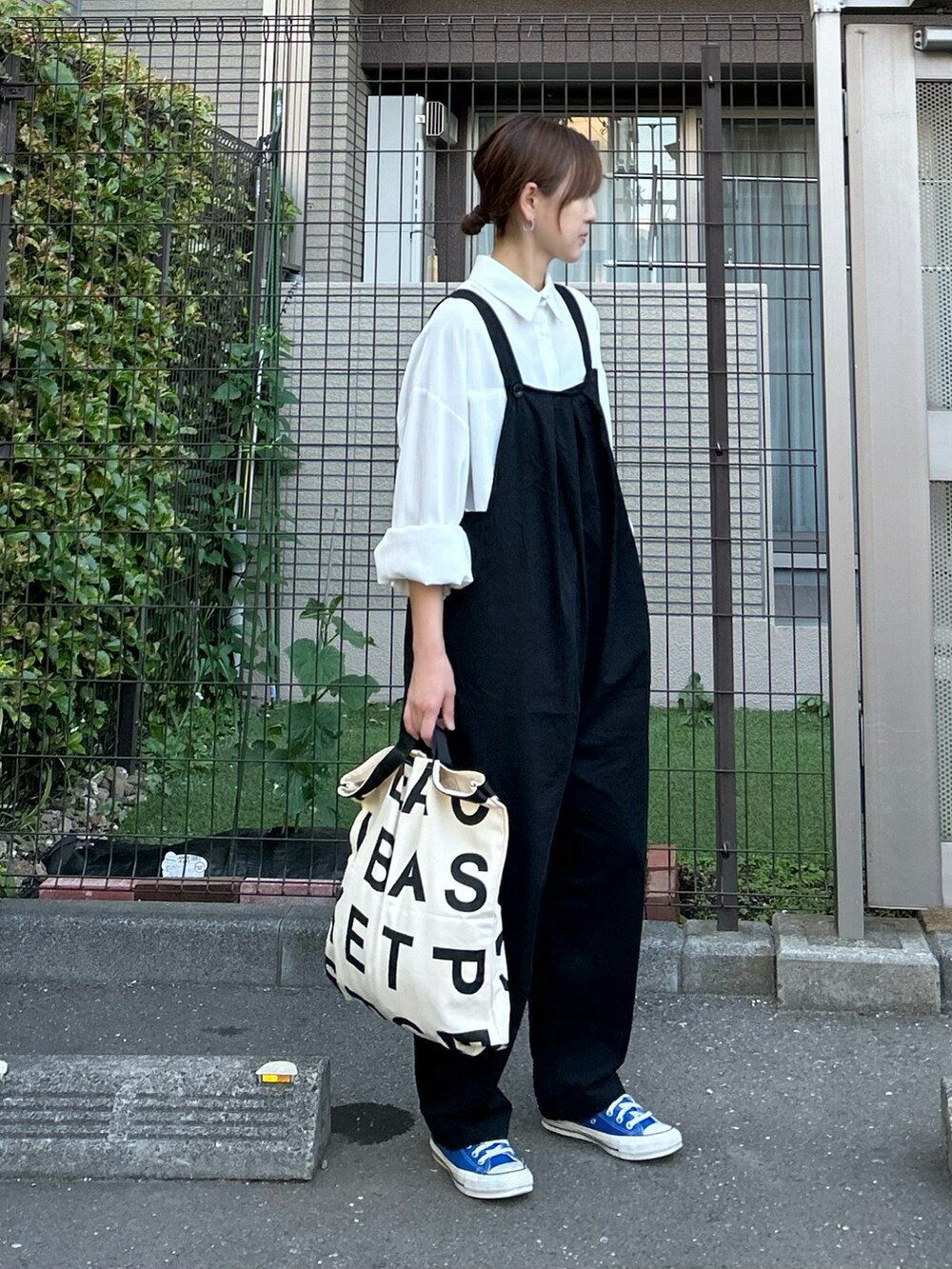 ホワイト系のシャツ/ブラウス、ブラック系のサロペット/オーバーオール、ブルー系のスニーカーを着用したレディースの春コーディネートの3枚目の写真