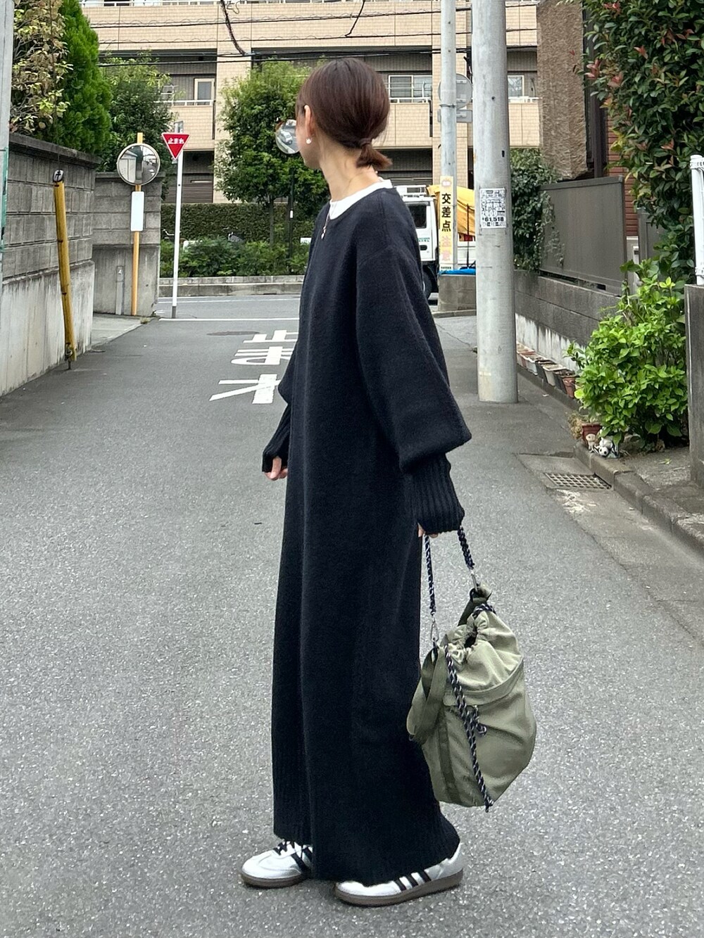 ブラック系のワンピース、グリーン系のショルダーバッグ、シルバー系のスニーカーを着用したレディースの秋コーディネートの4枚目の写真