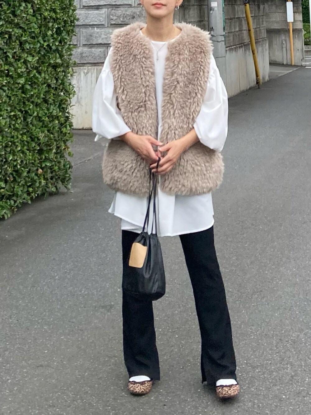 ベージュ系のベスト、ホワイト系のシャツ/ブラウス、ブラック系のハンドバッグを着用したレディースの秋コーディネートの2枚目の写真