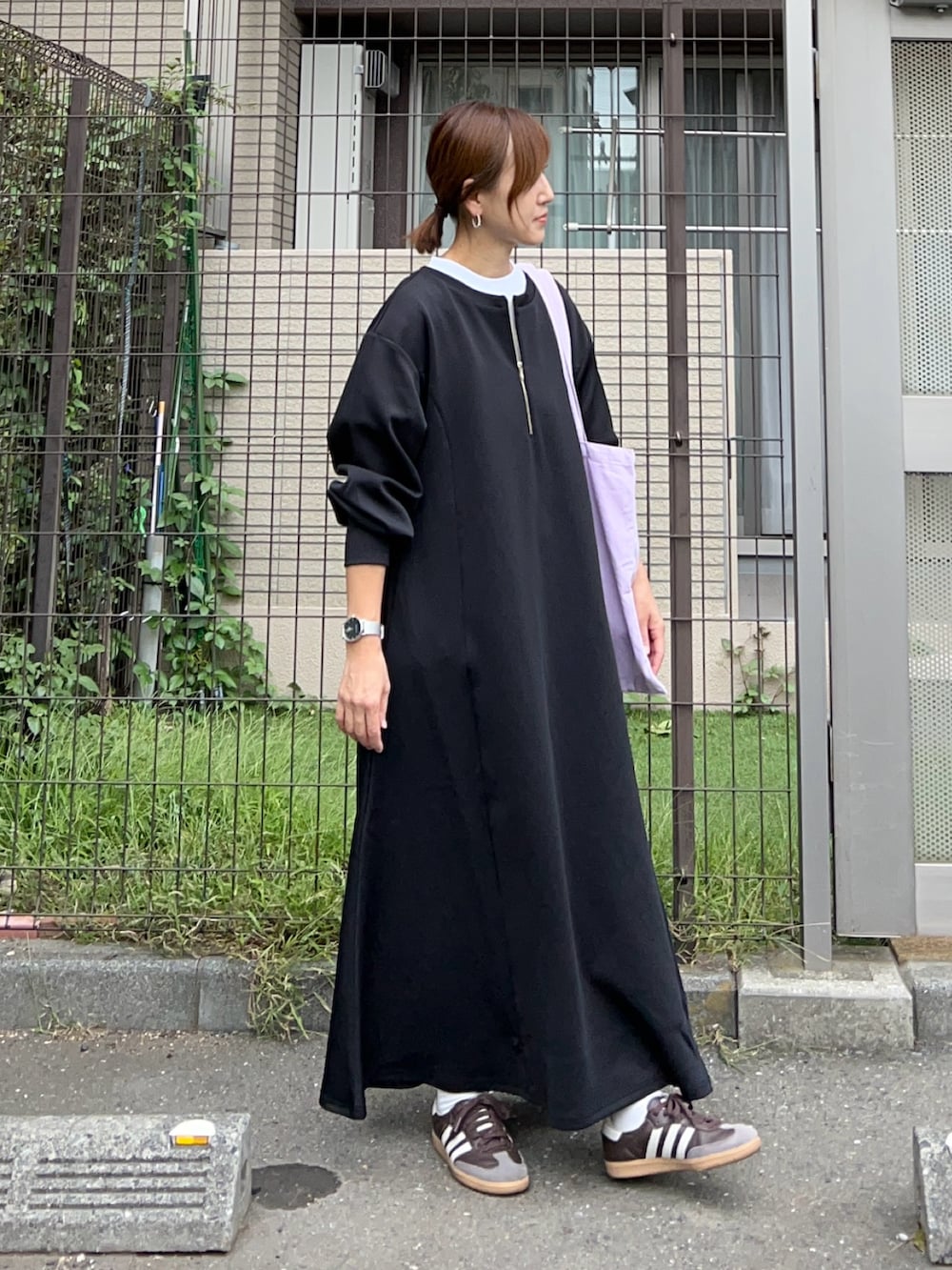 ブラック系のワンピース、オレンジ系のトートバッグ、ブラウン系のスニーカーを着用したレディースの秋コーディネートの4枚目の写真