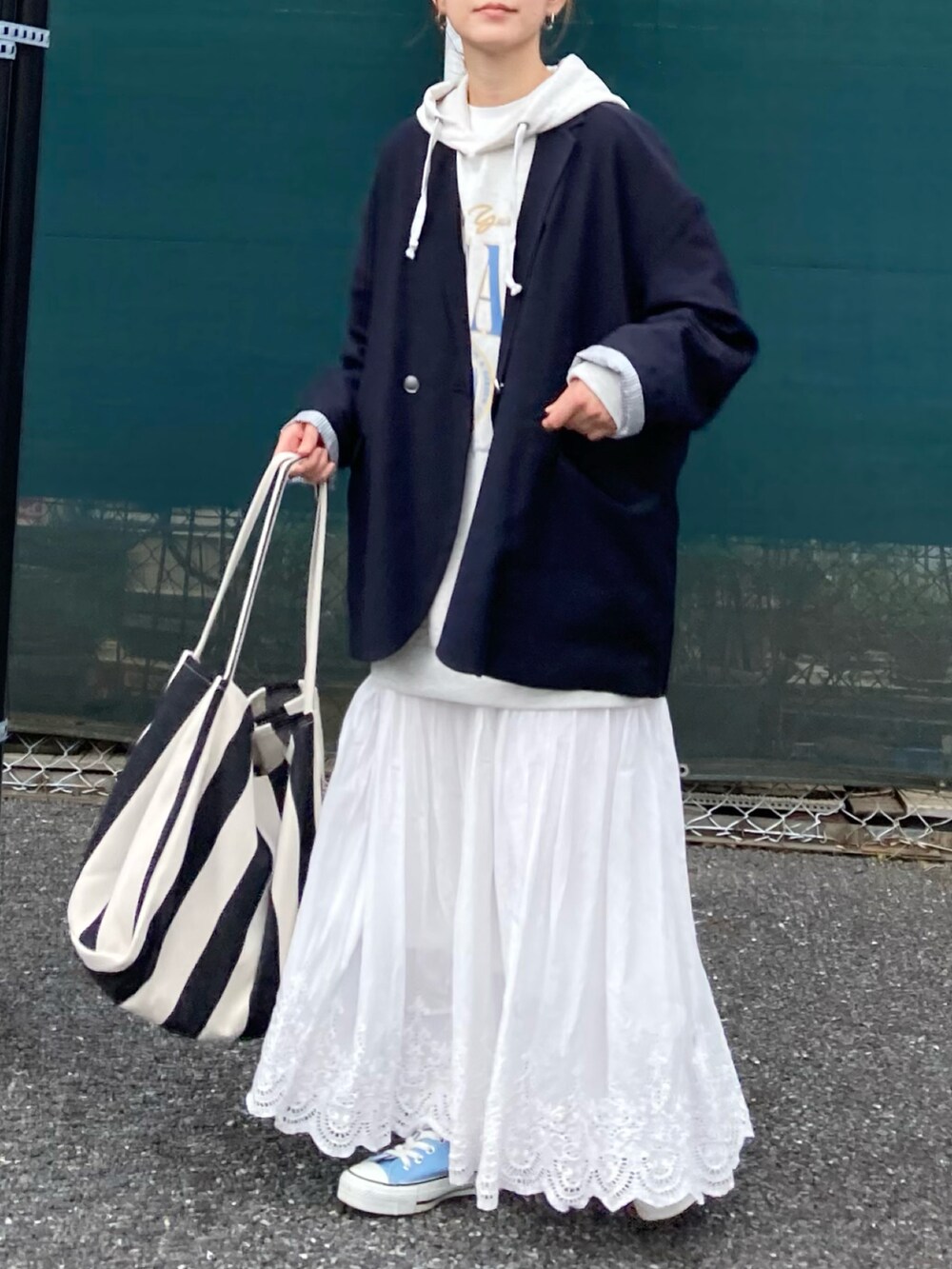 ベージュ系のパーカー、ホワイト系のスカート、ブラック系のトートバッグを着用したレディースの春コーディネートの2枚目の写真