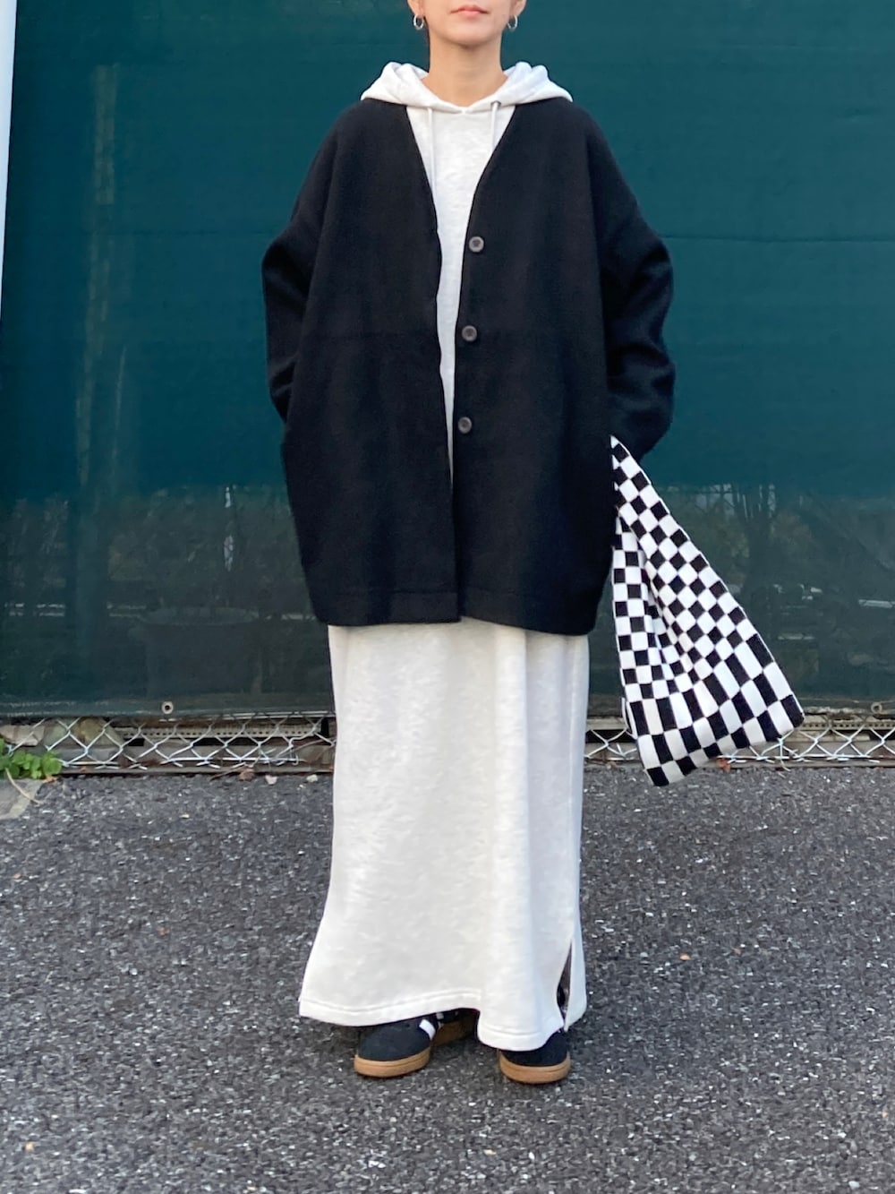 ブラック系のノーカラーコート、グレー系のワンピース、ブラック系のスニーカーを着用したレディースの冬コーディネートの4枚目の写真