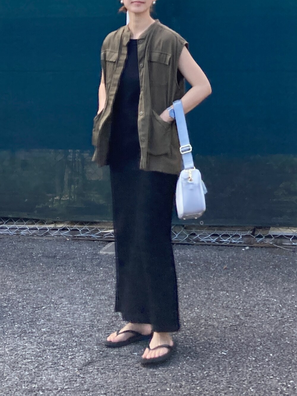 グリーン系のベスト、ブラック系のワンピース、ホワイト系のショルダーバッグを着用したレディースの夏コーディネートの2枚目の写真
