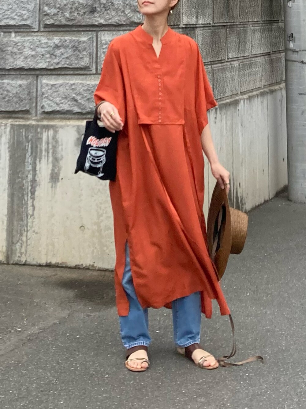 オレンジ系のシャツワンピースを着用したレディースの春コーディネートの3枚目の写真