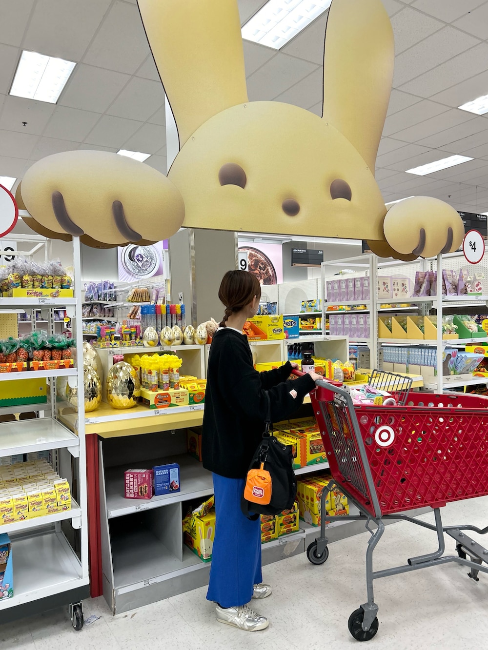 ブラック系のニット/セーター、ブルー系のスカート、ブラック系のショルダーバッグを着用したレディースの春コーディネートの3枚目の写真