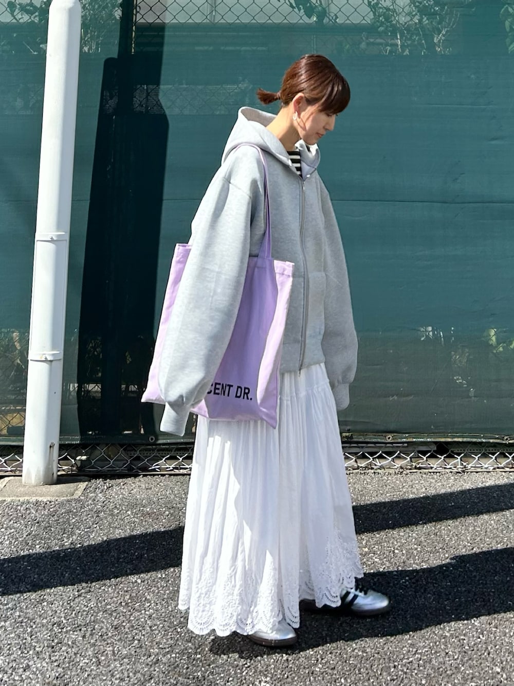 グレー系のパーカー、ホワイト系のスカート、パープル系のトートバッグを着用したレディースの秋コーディネートの4枚目の写真