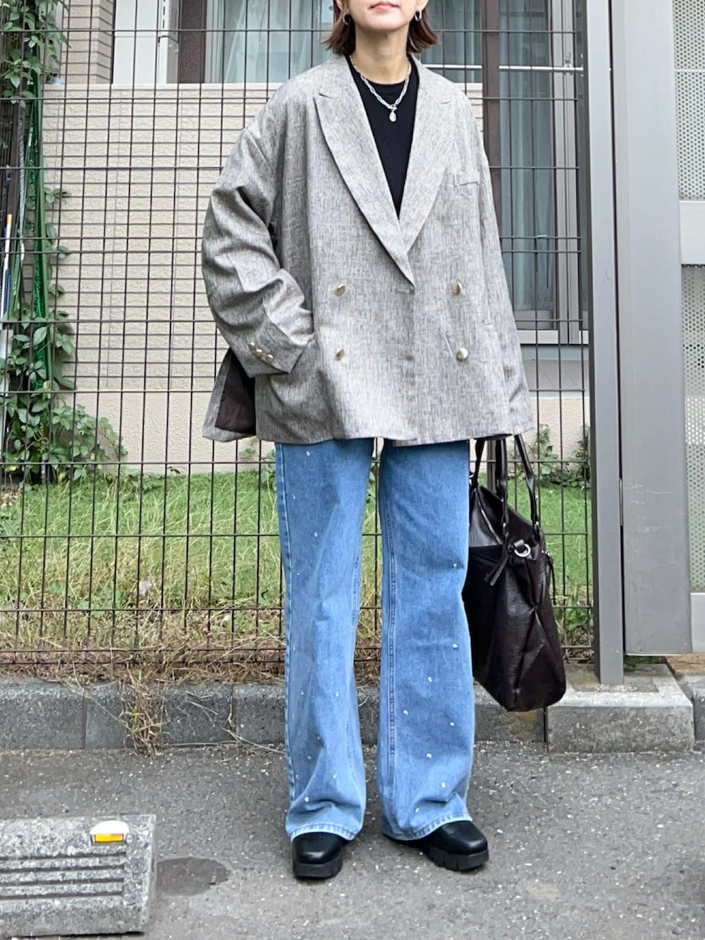 ベージュ系のテーラードジャケット、ブラウン系のトートバッグ、ブラック系のニット/セーターを着用したレディースの秋コーディネートの5枚目の写真