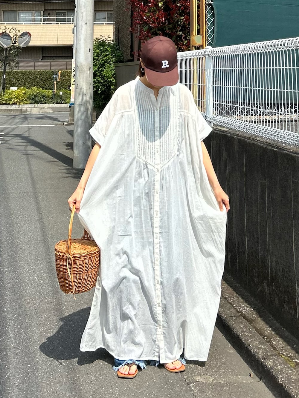 ホワイト系のワンピース、ブルー系のデニムパンツ、ブラウン系のキャップを着用したレディースの夏コーディネートの3枚目の写真