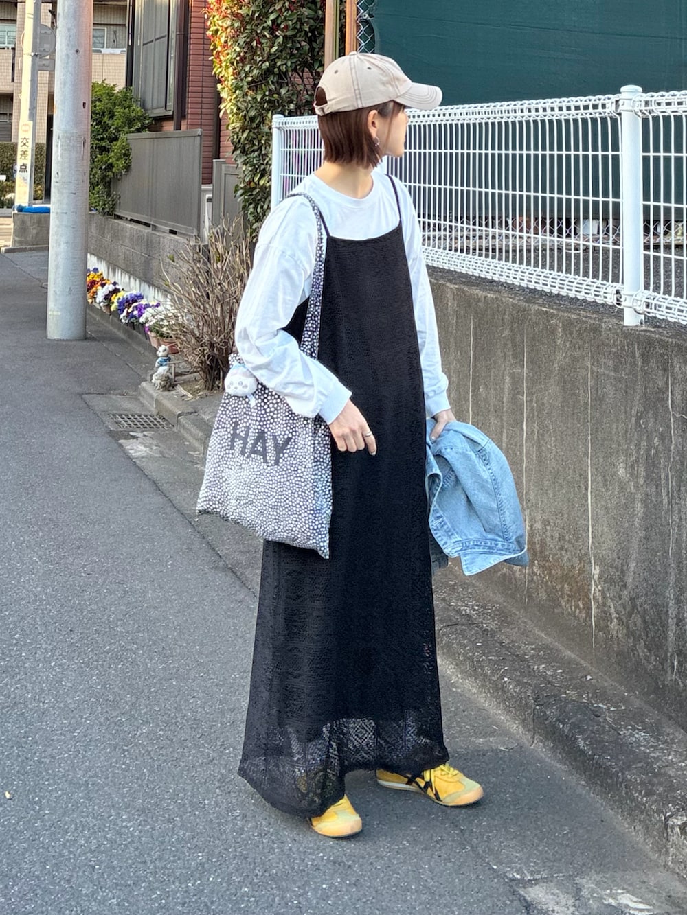 ブルー系のデニムジャケット、ブラック系のワンピース、イエロー系のスニーカーを着用したレディースの春コーディネートの4枚目の写真