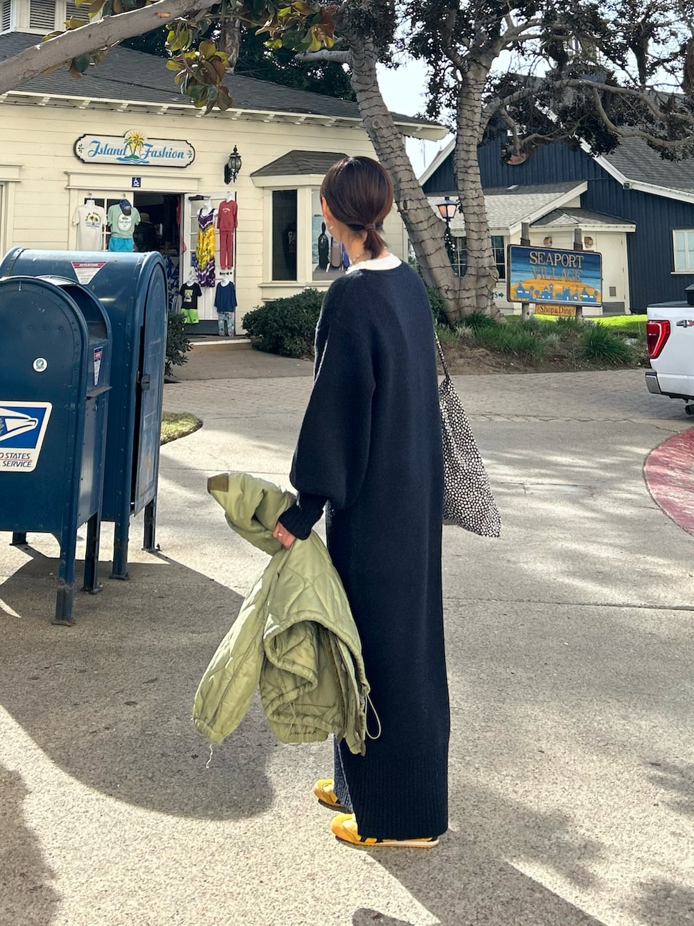 ブラック系のワンピース、グリーン系のノーカラージャケット、ブラック系のトートバッグを着用したレディースの冬コーディネートの2枚目の写真