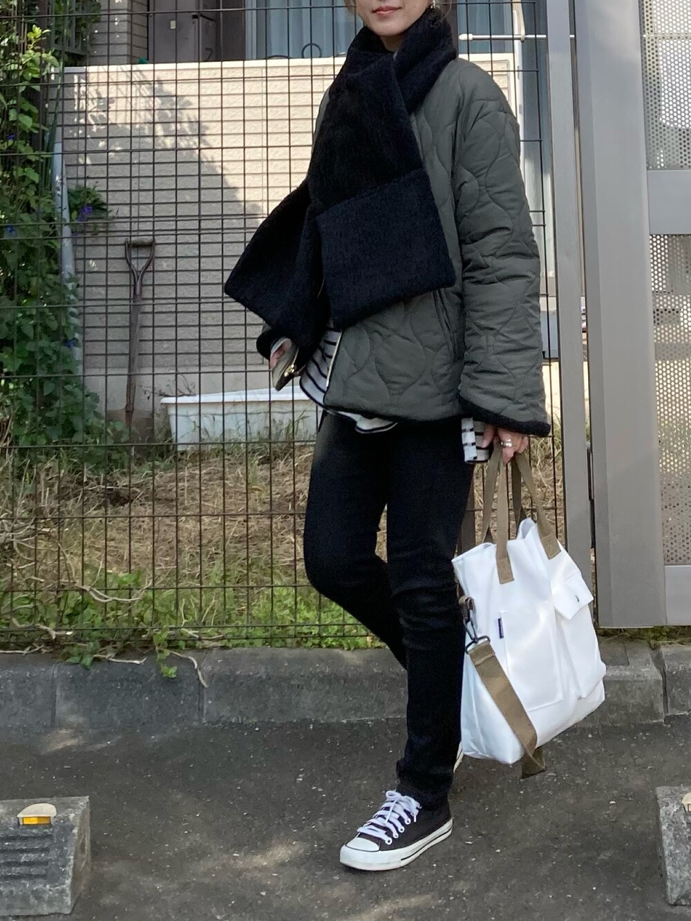 グリーン系のノーカラーコート、ホワイト系のトートバッグ、シルバー系のピアス（両耳用）を着用したレディースの秋コーディネートの3枚目の写真