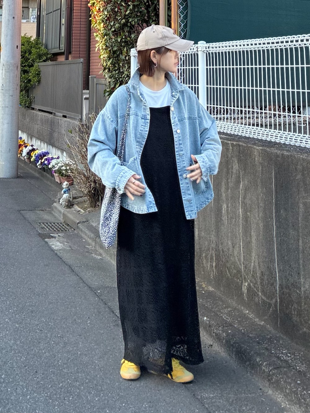 ブルー系のデニムジャケット、ブラック系のワンピース、イエロー系のスニーカーを着用したレディースの春コーディネートの2枚目の写真