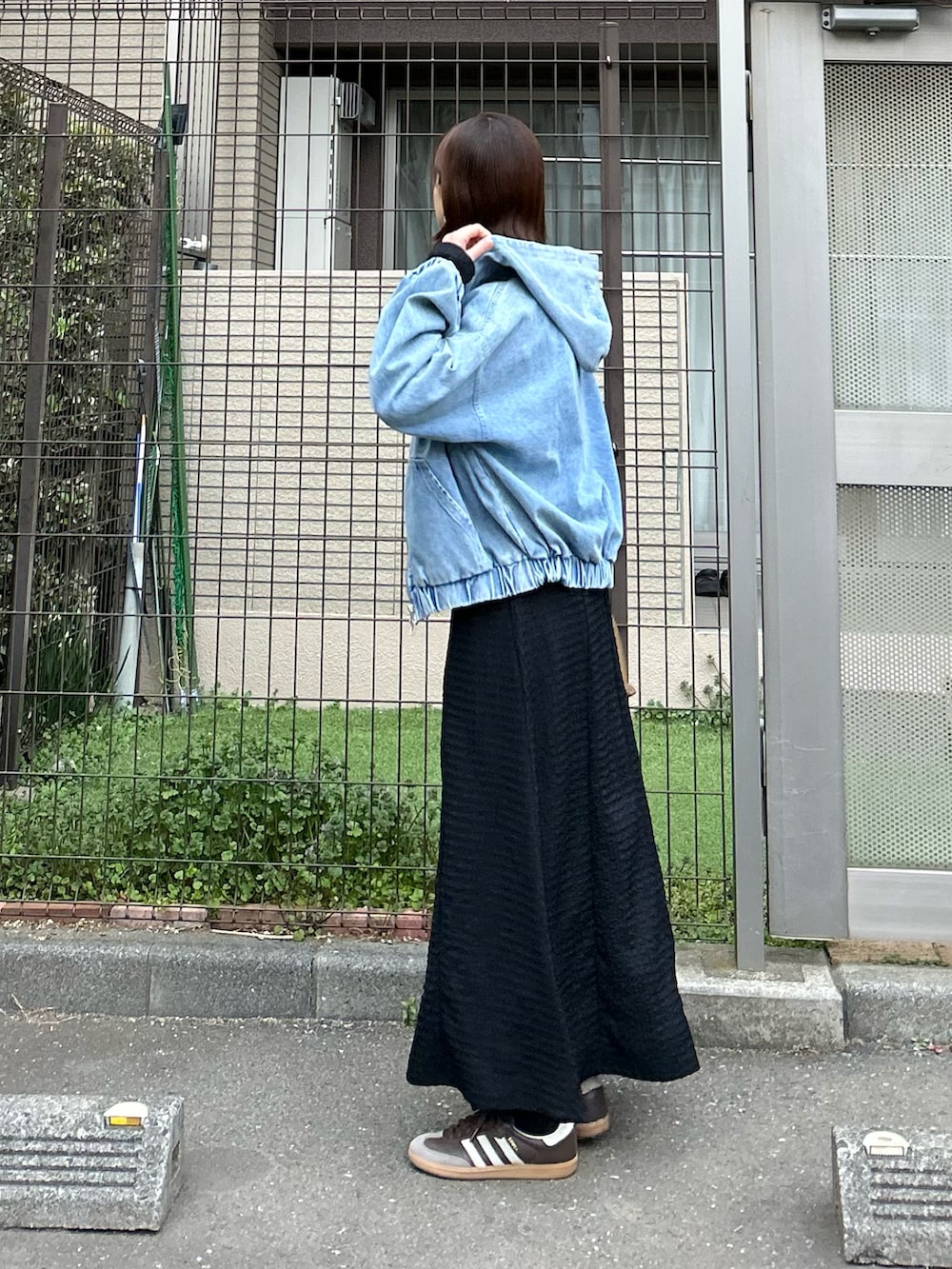 ブルー系のデニムジャケット、ブラック系のワンピース、ブラウン系のハンドバッグを着用したレディースの冬コーディネートの3枚目の写真