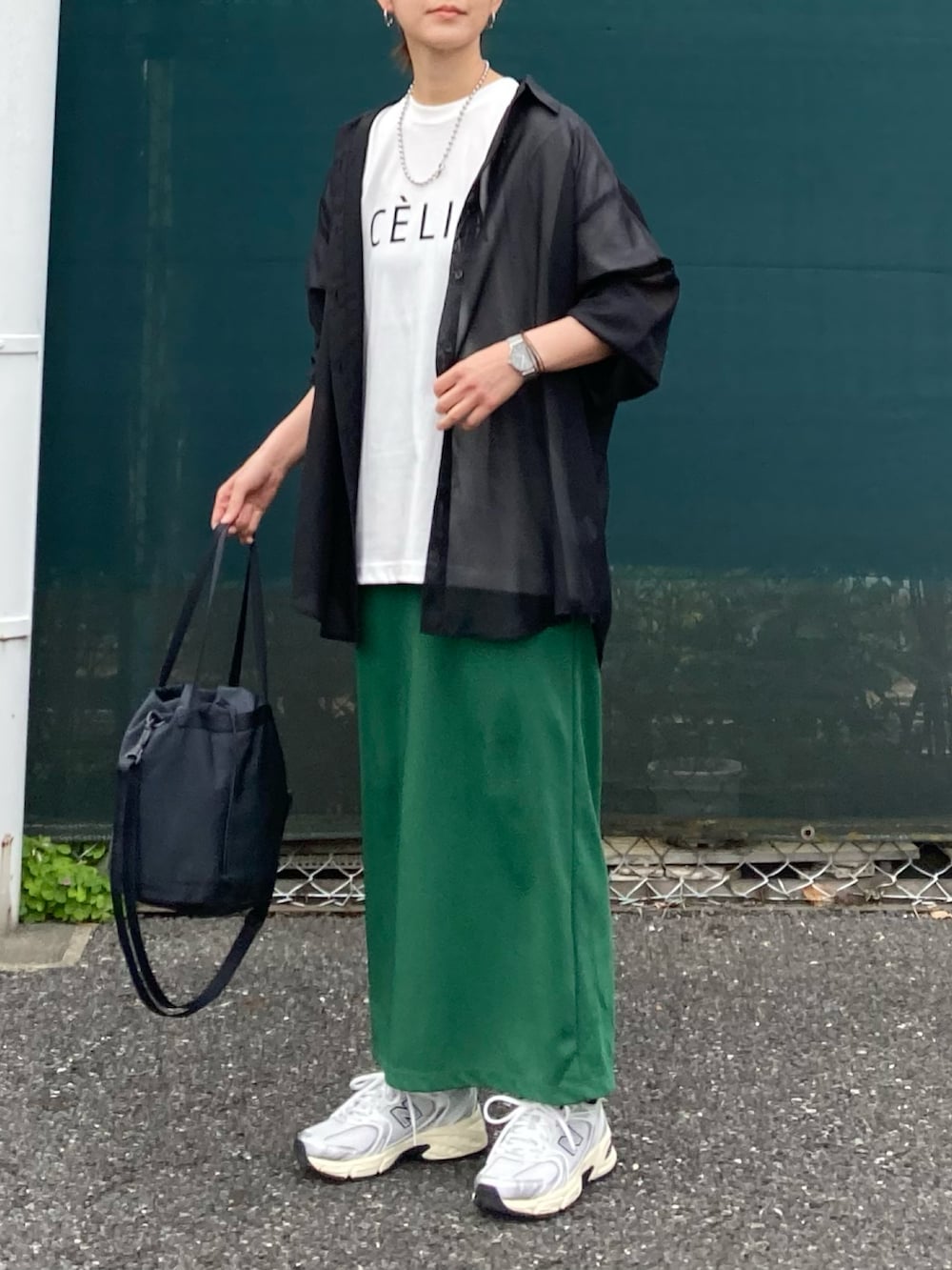 ブラック系のシャツ/ブラウス、グリーン系のスカート、ブラック系のバッグを着用したレディースの春コーディネートの2枚目の写真