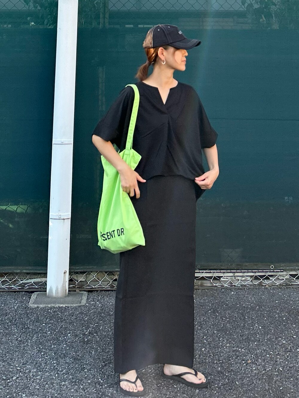 ブラック系のTシャツ/カットソー、ブラック系のスカート、グリーン系のトートバッグを着用したレディースの夏コーディネートの2枚目の写真