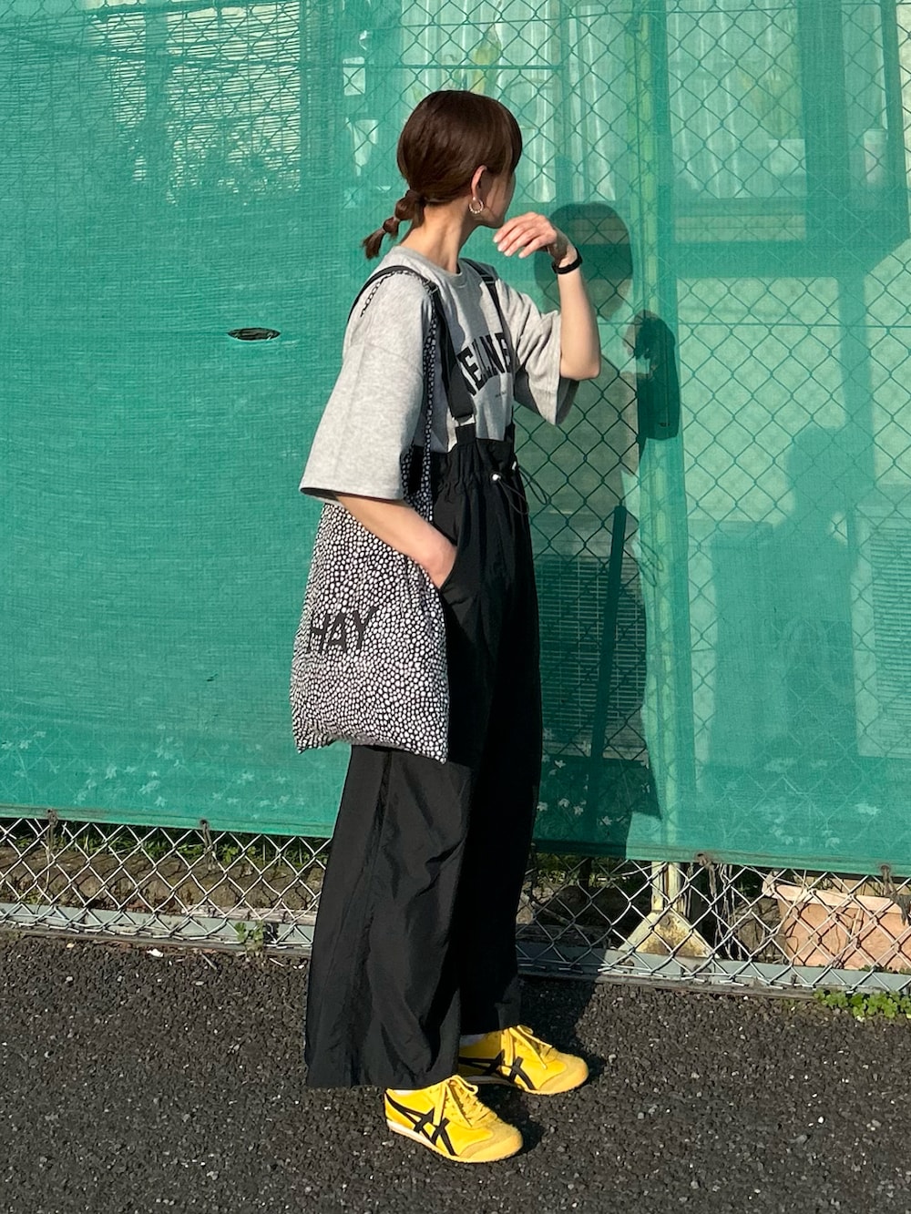 グレー系のTシャツ/カットソー、ブラック系のジャンパースカート、ブラック系のトートバッグを着用したレディースの春コーディネートの2枚目の写真