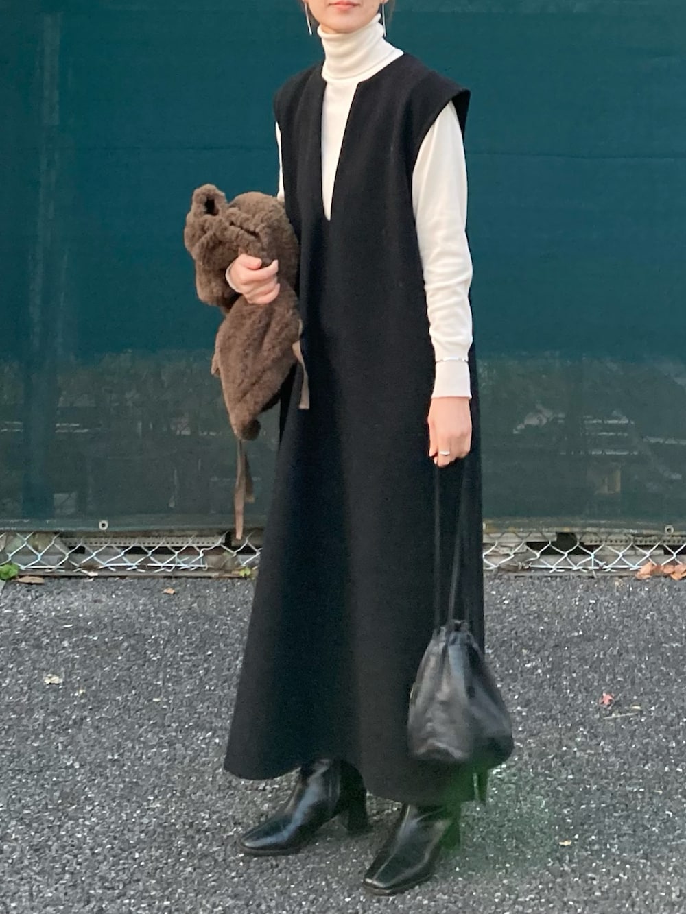 ブラック系のワンピース、ブラック系のハンドバッグ、ブラック系のブーツを着用したレディースの冬コーディネートの2枚目の写真