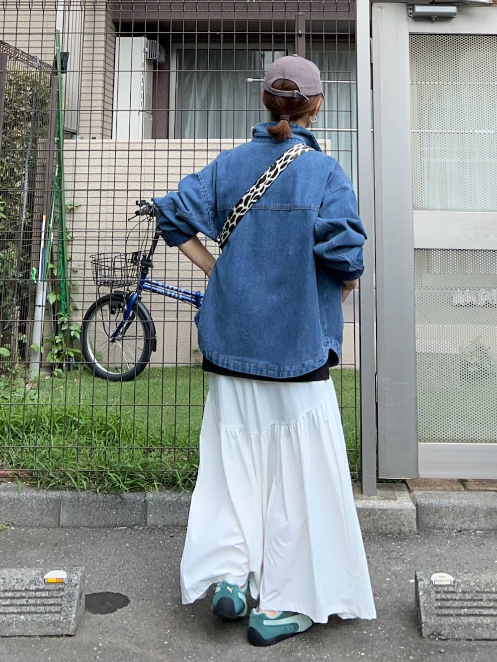 ブルー系のデニムジャケット、ブラック系のボディバッグ/ウエストポーチ、グリーン系のスニーカーを着用したレディースの秋コーディネートの4枚目の写真