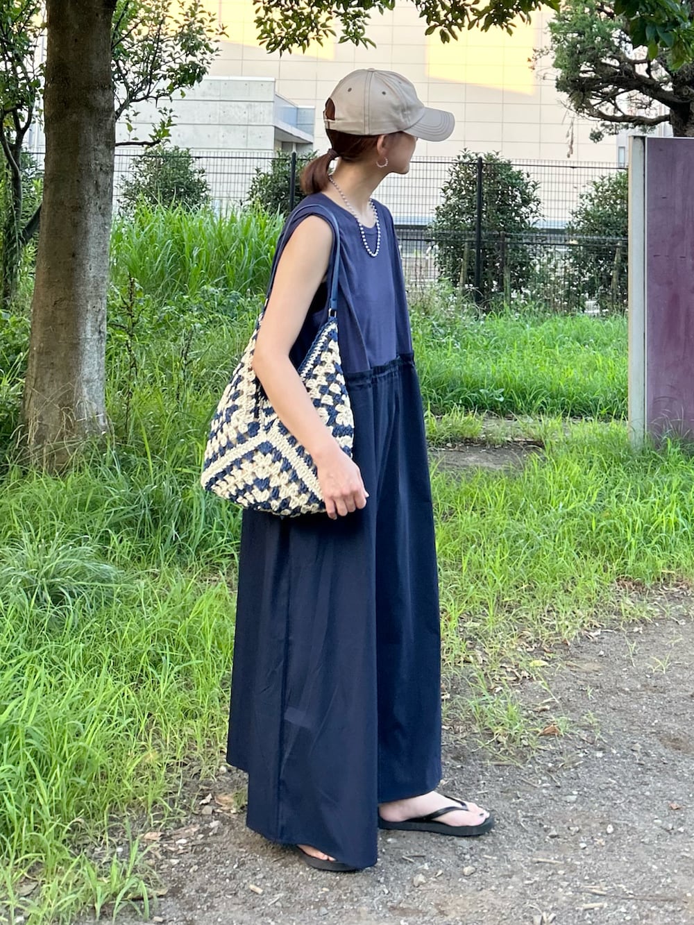 ブルー系のワンピース、ブルー系のかごバッグ、ベージュ系のキャップを着用したレディースの夏コーディネートの3枚目の写真