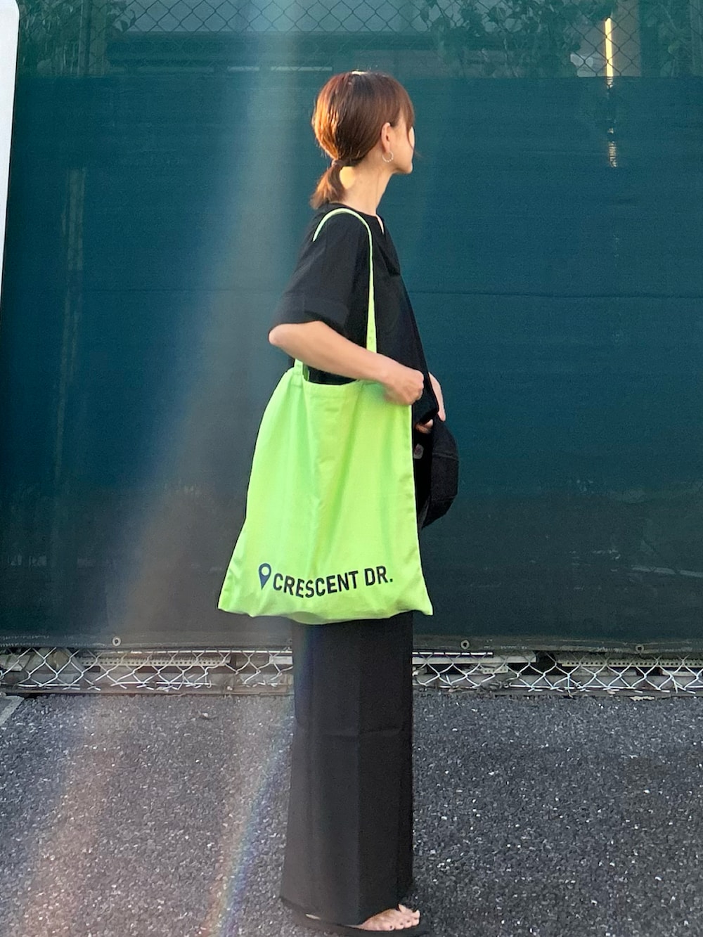 ブラック系のTシャツ/カットソー、ブラック系のスカート、グリーン系のトートバッグを着用したレディースの夏コーディネートの4枚目の写真