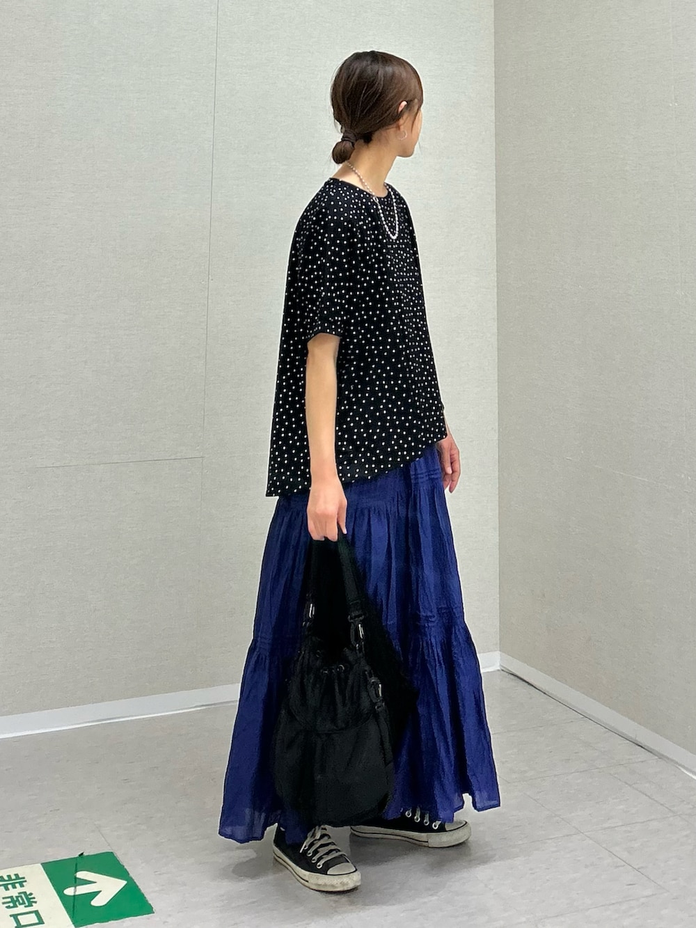 ブラック系のTシャツ/カットソー、ブルー系のスカート、ブラック系のショルダーバッグを着用したレディースの春コーディネートの4枚目の写真