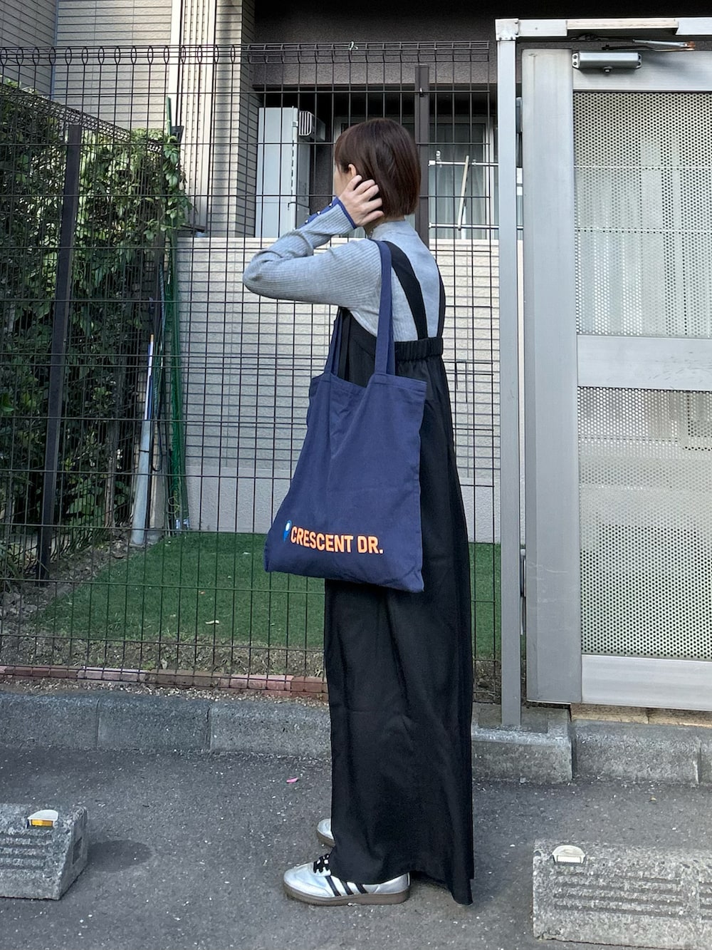 ブラック系のサロペット/オーバーオール、ブルー系のトートバッグ、グレー系のニット/セーターを着用したレディースの冬コーディネートの3枚目の写真