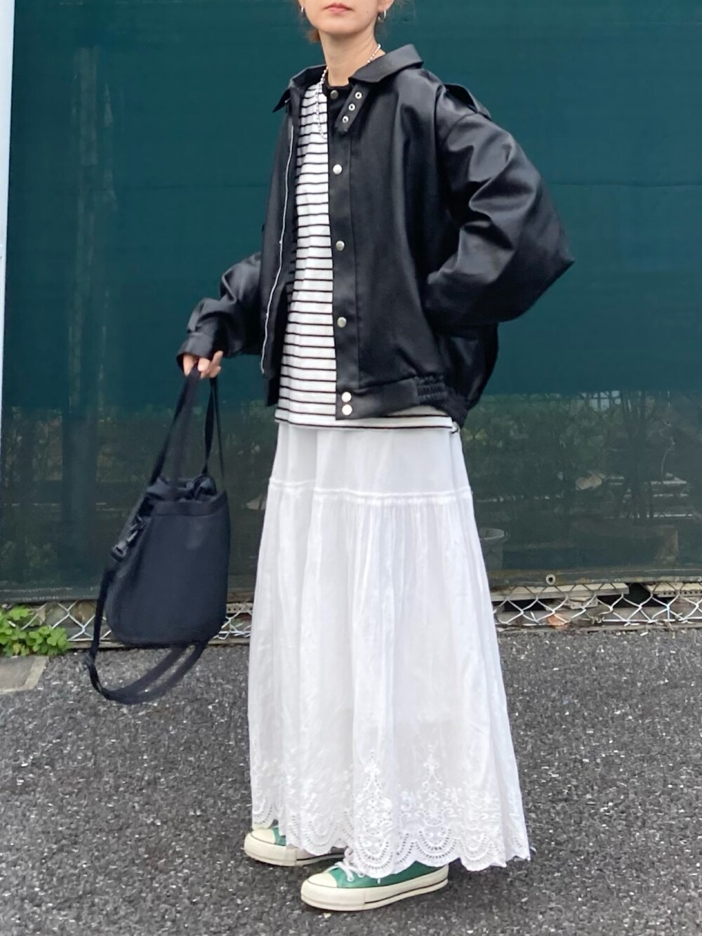 ブラック系のブルゾン、ブラック系のTシャツ/カットソー、ホワイト系のスカートを着用したレディースの春コーディネートの5枚目の写真