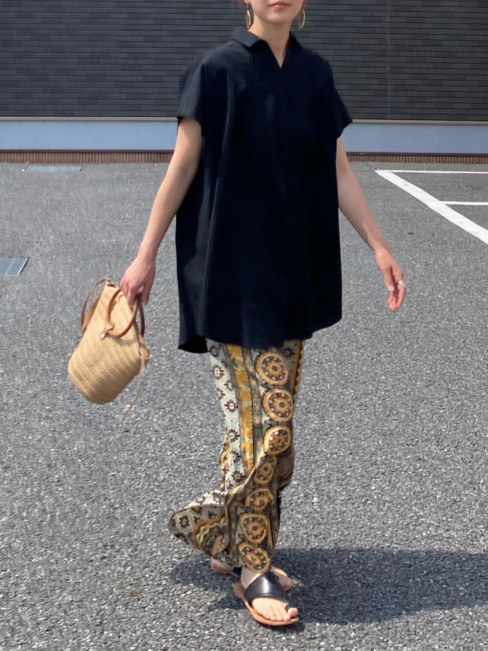 ブラック系のその他トップス、イエロー系のその他パンツ、ベージュ系のかごバッグを着用したレディースの夏コーディネートの2枚目の写真