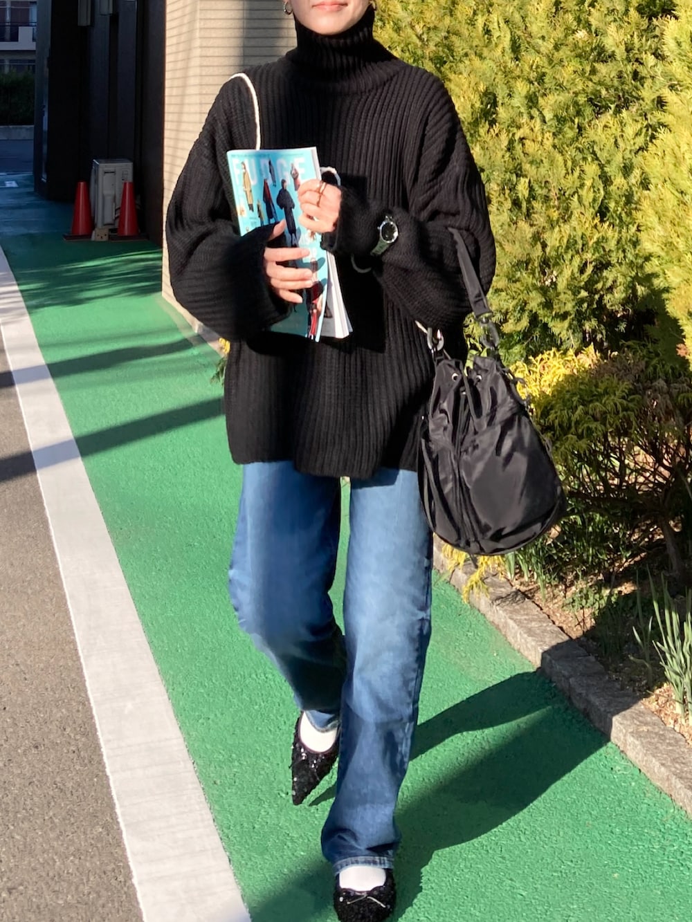 ブラック系のニット/セーター、ブルー系のデニムパンツ、ブラック系のショルダーバッグを着用したレディースの冬コーディネートの5枚目の写真