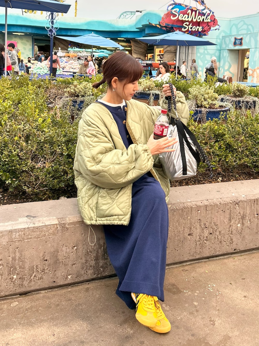 グリーン系のノーカラージャケット、ブルー系のワンピース、シルバー系のトートバッグを着用したレディースの冬コーディネートの2枚目の写真