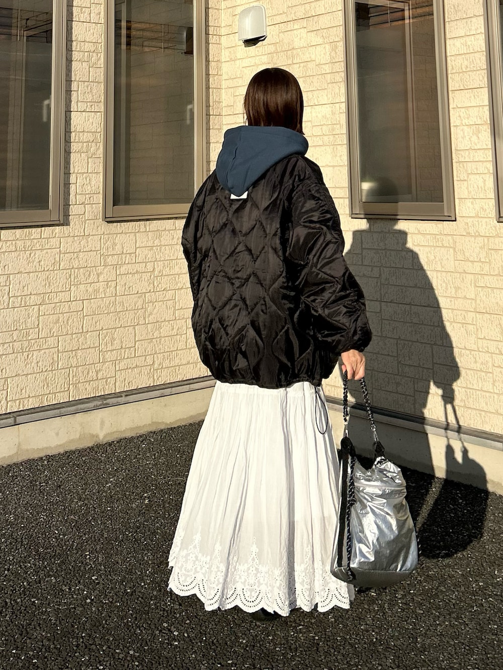 ブラック系のブルゾン、ブルー系のパーカー、シルバー系のトートバッグを着用したレディースの冬コーディネートの5枚目の写真