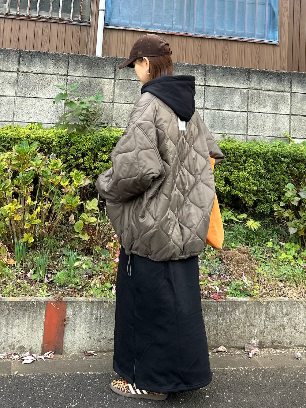 ブラウン系のブルゾン、ブラック系のワンピース、オレンジ系のトートバッグを着用したレディースの冬コーディネートの5枚目の写真