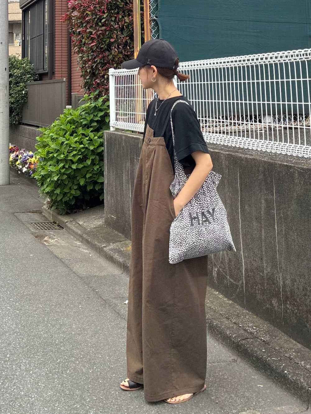 ブラック系のTシャツ/カットソー、ブラウン系のサロペット/オーバーオール、ブラック系のキャップを着用したレディースの春コーディネートの2枚目の写真