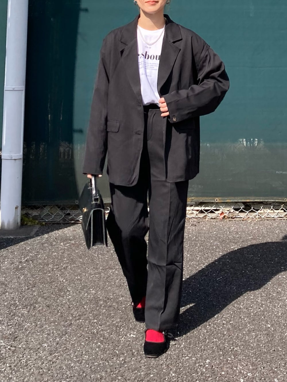 ブラック系のセットアップ、ホワイト系のTシャツ/カットソー、ブラック系のショルダーバッグを着用したレディースの冬コーディネートの2枚目の写真