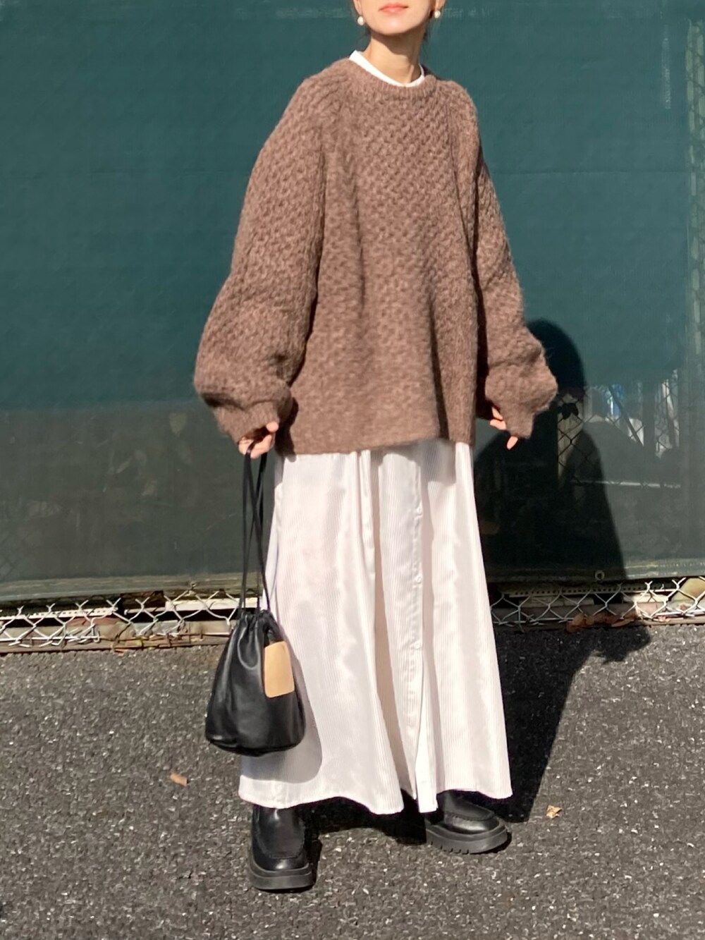 ブラウン系のニット/セーター、ベージュ系のワンピース、ブラック系のハンドバッグを着用したレディースの冬コーディネートの3枚目の写真