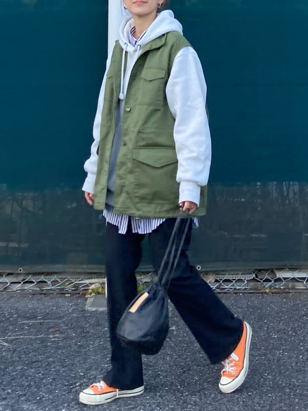 グリーン系のベスト、グレー系のパーカー、ブラック系のスラックスを着用したレディースの冬コーディネートの5枚目の写真