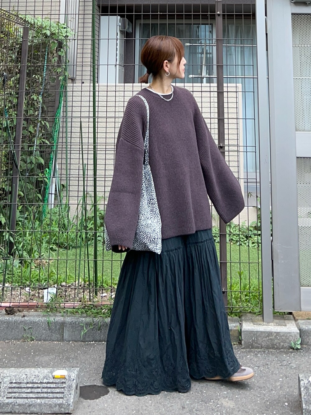 ブラウン系のニット/セーター、ブラック系のスカート、ブラウン系のスニーカーを着用したレディースの夏コーディネートの2枚目の写真