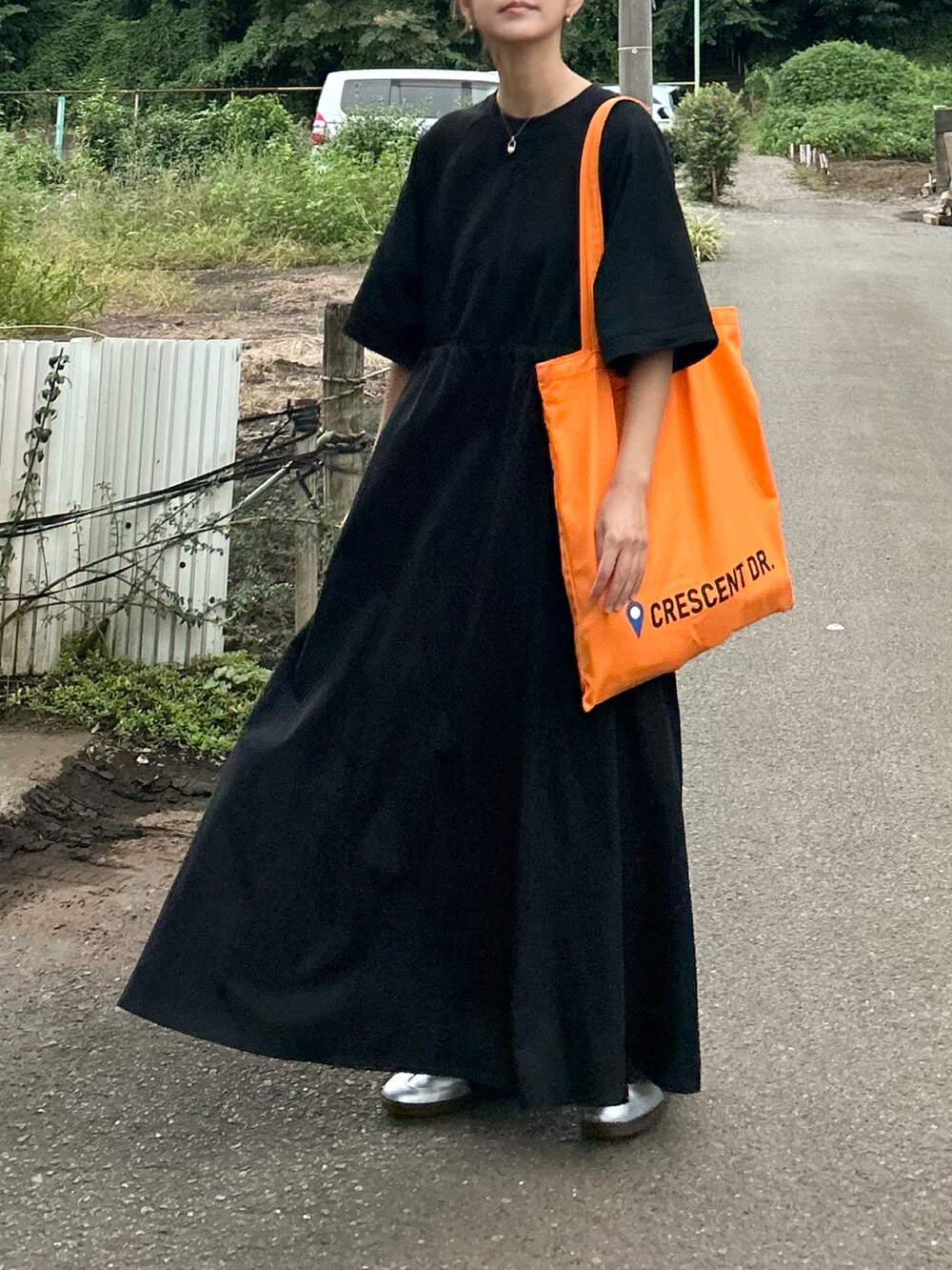 ブラック系のワンピース、オレンジ系のトートバッグ、シルバー系のスニーカーを着用したレディースの秋コーディネートの4枚目の写真