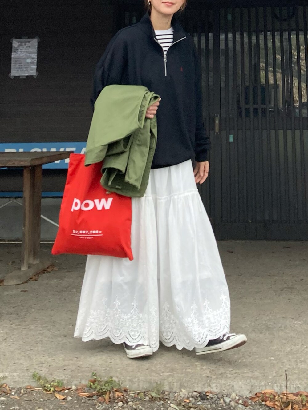 ブラック系のスウェット、ホワイト系のスカート、レッド系のトートバッグを着用したレディースの冬コーディネートの2枚目の写真