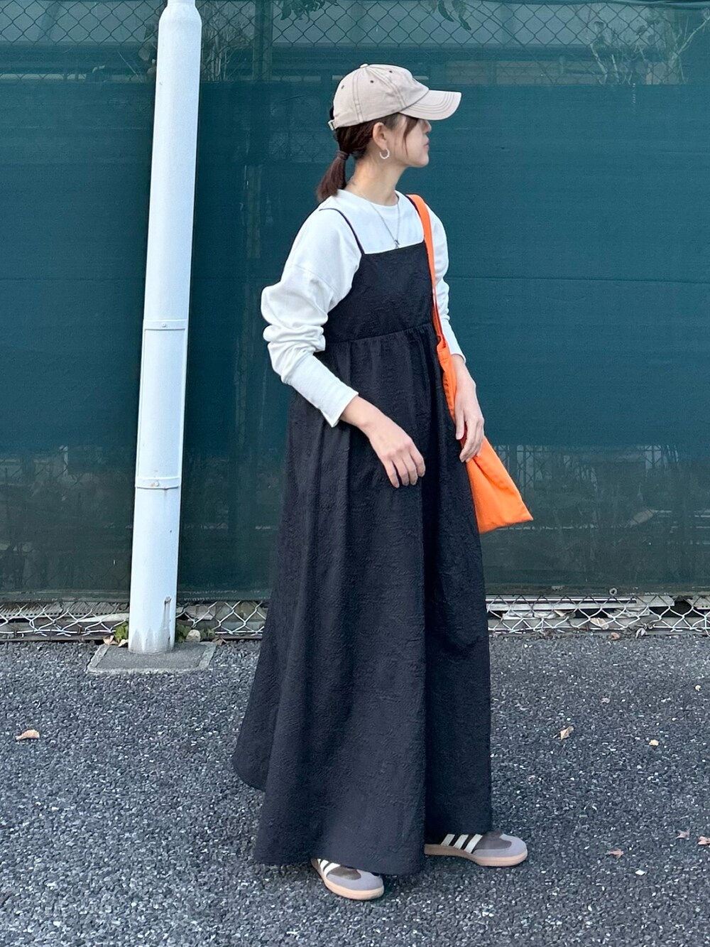ブラック系のワンピース、オレンジ系のトートバッグを着用したレディースの冬コーディネートの2枚目の写真