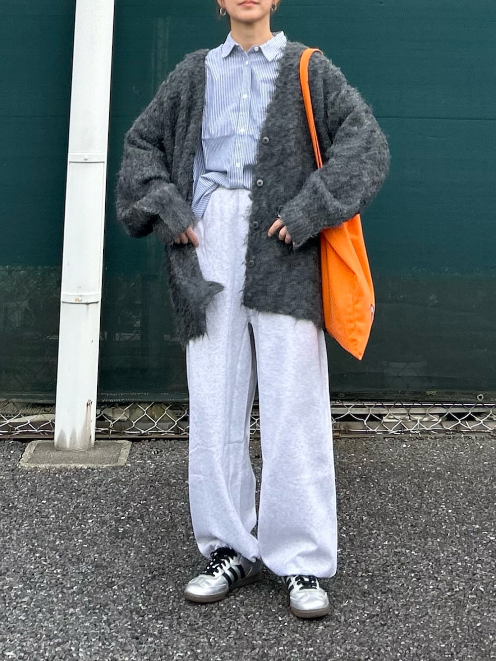 グレー系のカーディガン/ボレロ、ブルー系のシャツ/ブラウス、オレンジ系のトートバッグを着用したレディースの秋コーディネートの2枚目の写真
