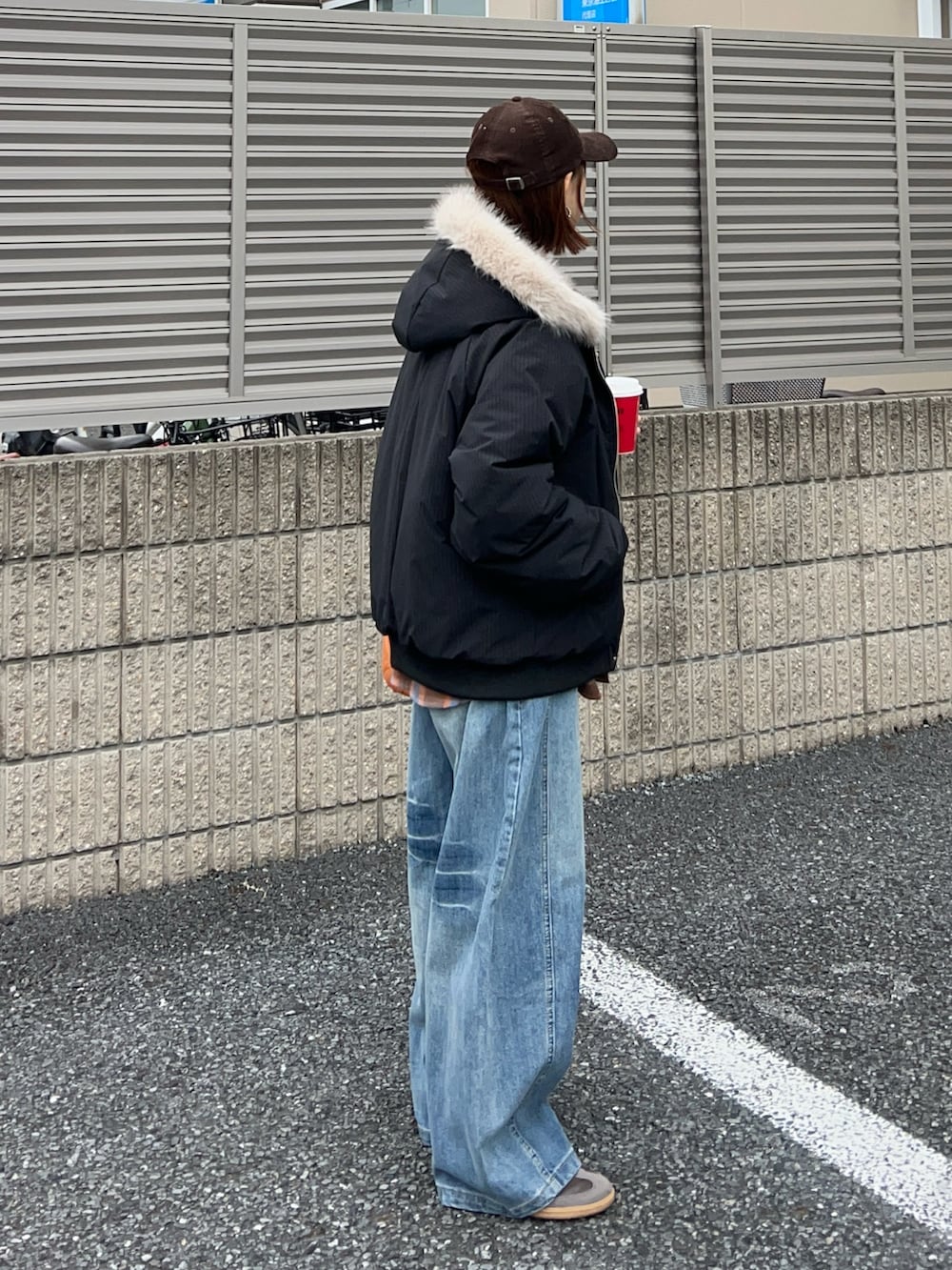 オレンジ系のショルダーバッグ、ブラウン系のスニーカー、ブラック系のその他アウターを着用したレディースの冬コーディネートの4枚目の写真