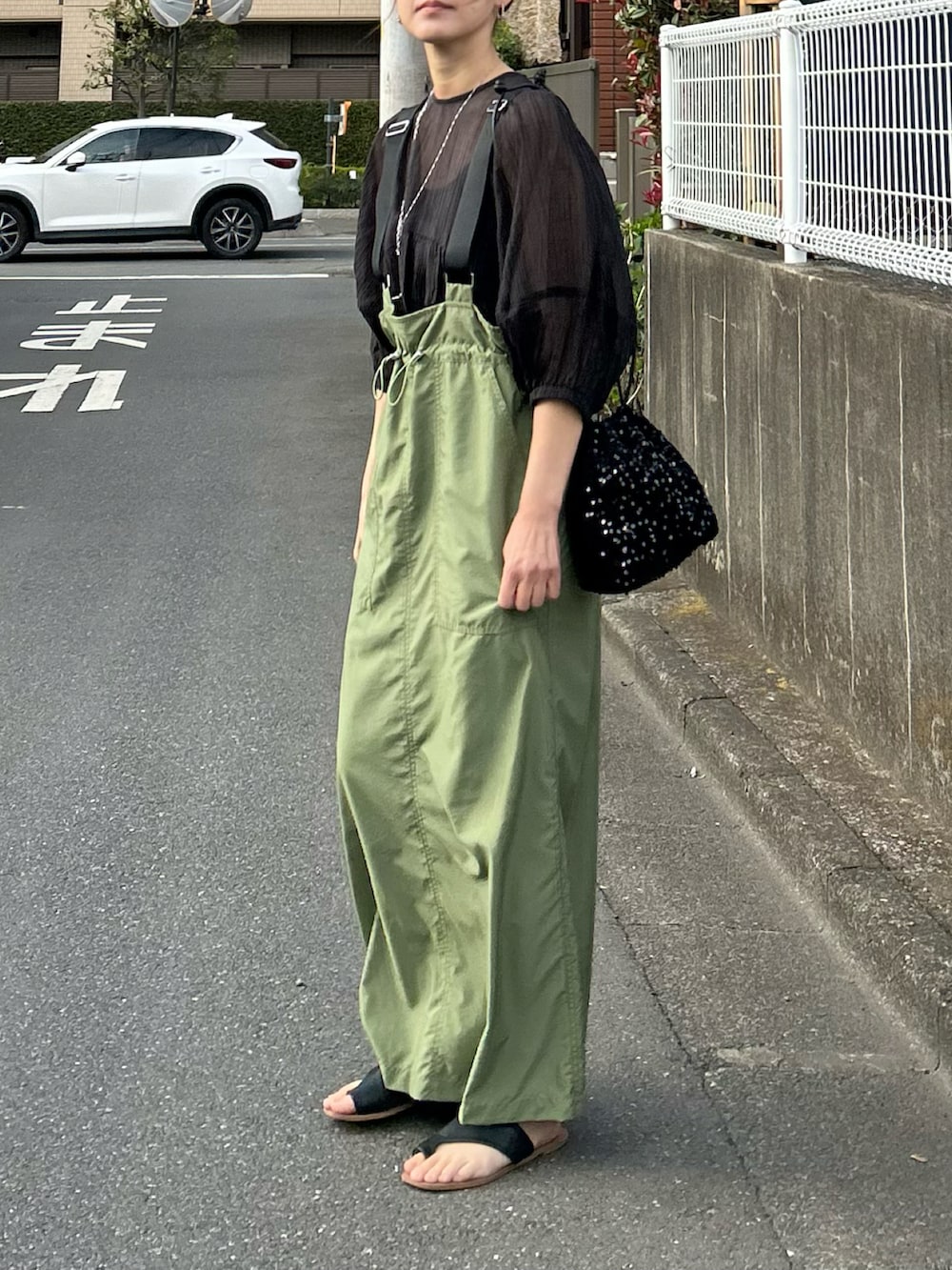 グリーン系のジャンパースカート、ブラック系のシャツ/ブラウス、ブラック系のショルダーバッグを着用したレディースの春コーディネートの3枚目の写真